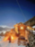 A stunning on-mountain restaurant called "Berghutte" lit up at night.