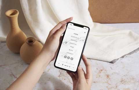 Hands holding a mobile phone displaying the Bieze Design menu.
