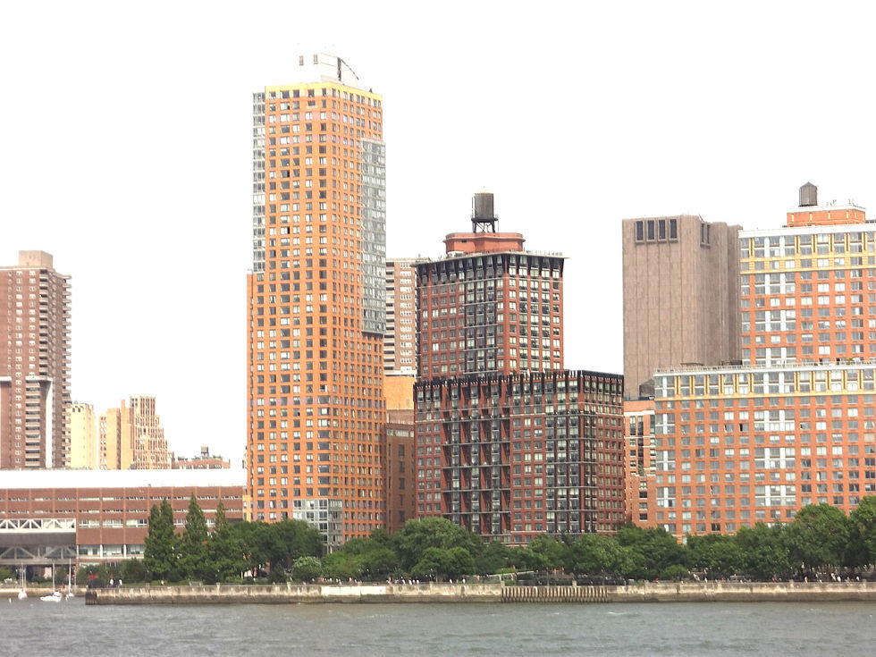 Do outro lado do rio, Manhattan desenha seu perfil mais humano em tons de terracota e ocre. São os residential complexes que abraçam milhares de vidas cotidianas, cada janela uma pequena biografia urbana. As torres de apartamentos se erguem como colmeias verticais, onde brasileiros, dominicanos, chineses e nova-iorquinos nativos compartilham elevadores e sonhos. A água do East River espelha essas fachadas avermelhadas, criando uma Nova York mais acessível, menos intimidante - aquela onde realmente se vive, não apenas se trabalha. É a cidade dos imigrantes, vista da perspectiva de quem ainda sonha em pertencer.