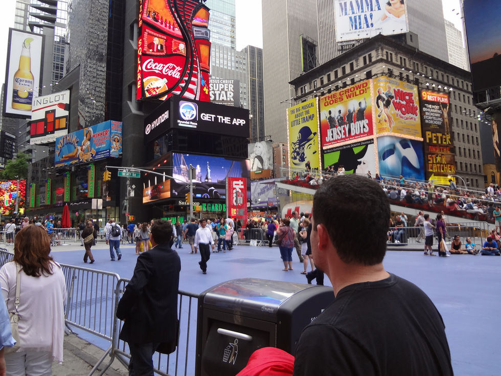 Times Square se transforma em uma galeria a céu aberto onde Jesus Cristo Superstar dialoga com Jersey Boys numa sinfonia de cores e promessas. Coca-Cola derrama sua marca vermelha como sangue vital da cidade, enquanto a multidão peregrina pelas escadarias azuis desta catedral secular onde cada musical é uma oração cantada aos céus urbanos.