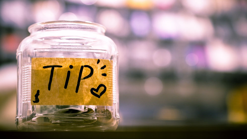 a clear glass tipping jar with a sticker that reads "tip".