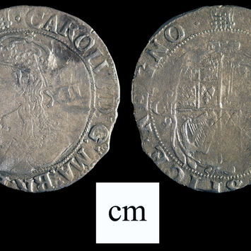 Reverse and obverse views of a King Charles I silver shilling (ca. 1633/1634) on a black background