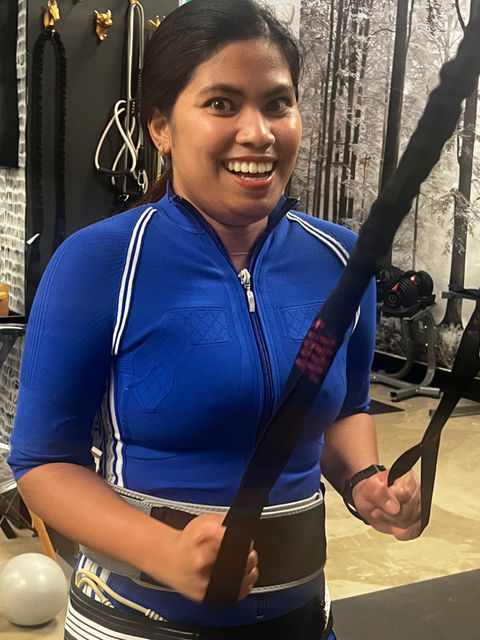 Happy woman preforming a workout with TRX and EMS