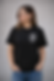 Femme souriante, t-shirt noir imprimé "TON LOGO ICI", mains dans poches.