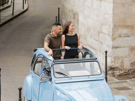 Couple in a blue 1978 2CV on a cobbled Paris street