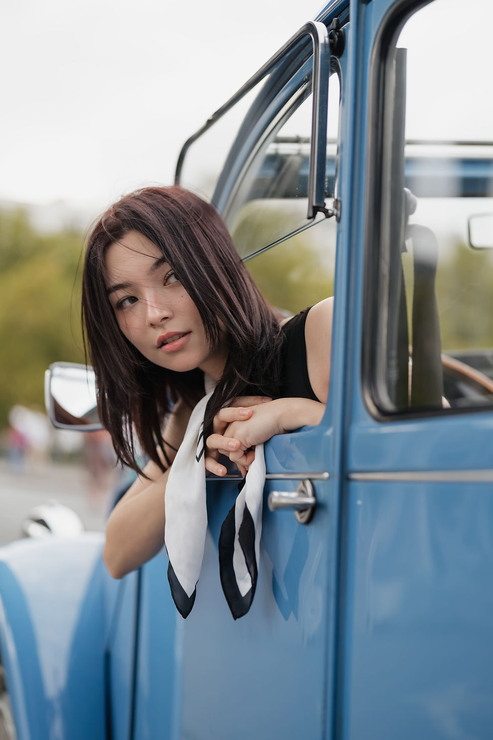 Young woman leaning on the door of a blue 2CV, photo shoot in Paris