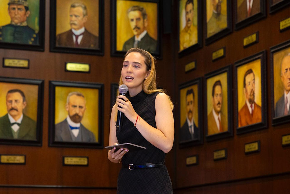 Virginia Hernández Vázquez informa sobre el exitoso programa educativo que cubre el 100% de las escuelas públicas de bachillerato, durante una conferencia en un recinto adornado con retratos históricos. Se han impartido más de 2 mil capacitaciones a docentes y padres de familia.