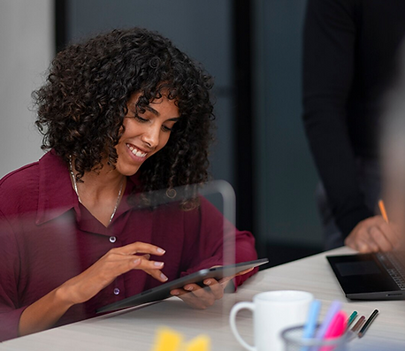 Mulher sorridente utilizando um tablet em ambiente profissional, representando facilidade de uso do aplicativo de terapia OM myself para terapeutas.