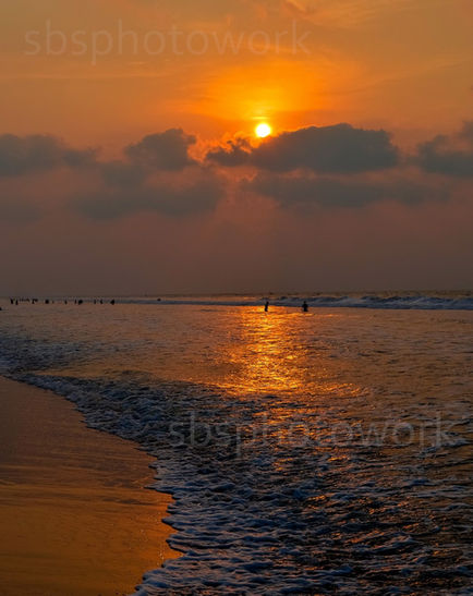 Sunset over ocean waves with cloudy sky.