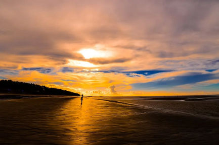 Sunset over beach with vibrant orange and blue sky.