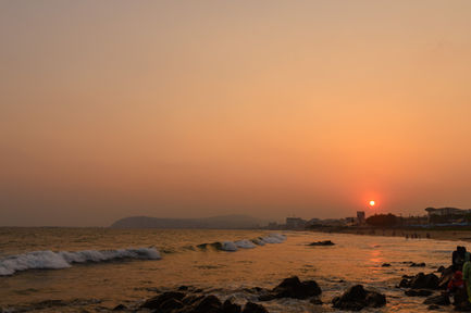 Sunset over a rocky beach with gentle waves.