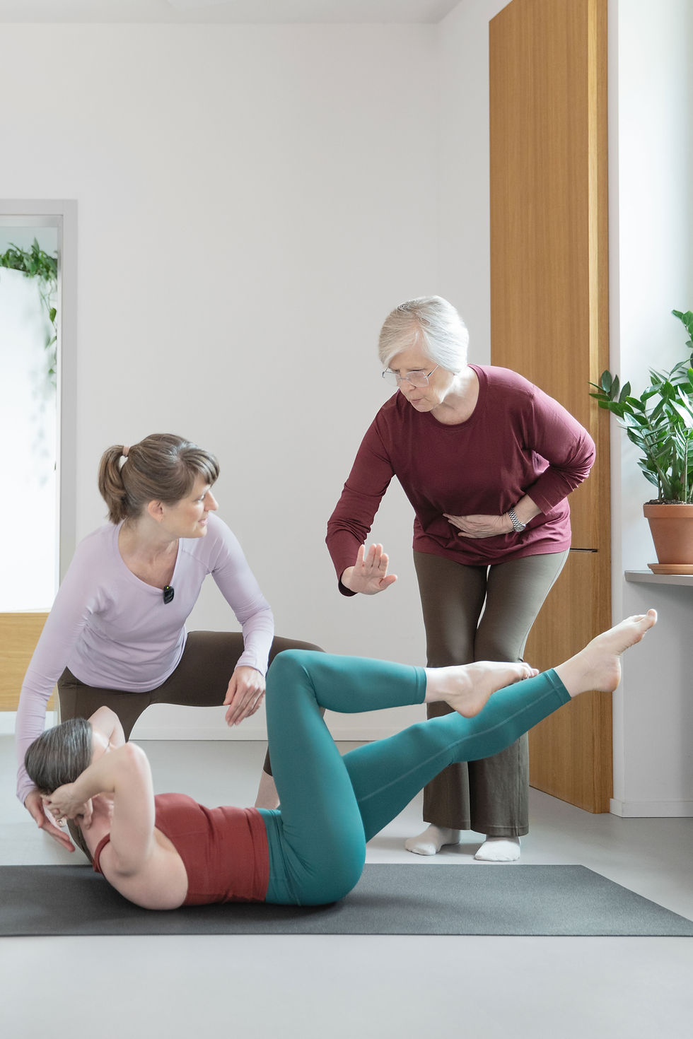 Trainerin leitet gehörlose Teilnehmerin mit Unterstützung einer Gebärdendolmetscherin in der Pilates Stube an