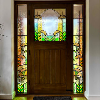 A modern and abstract front door set of 2 full height side lights and large door light. The design incorporated stylised achillea flowers and botanical leaves and grasses. Details are a mix of glass paints and sandblasting work. The design and colour is concentrated at the bottom of the panels to create a flow and allow more light through at the top. The finished leaded panels have been encapsulated in 28mm double glazed units before installation. Hand madly Seaview Studio, Hampshire.