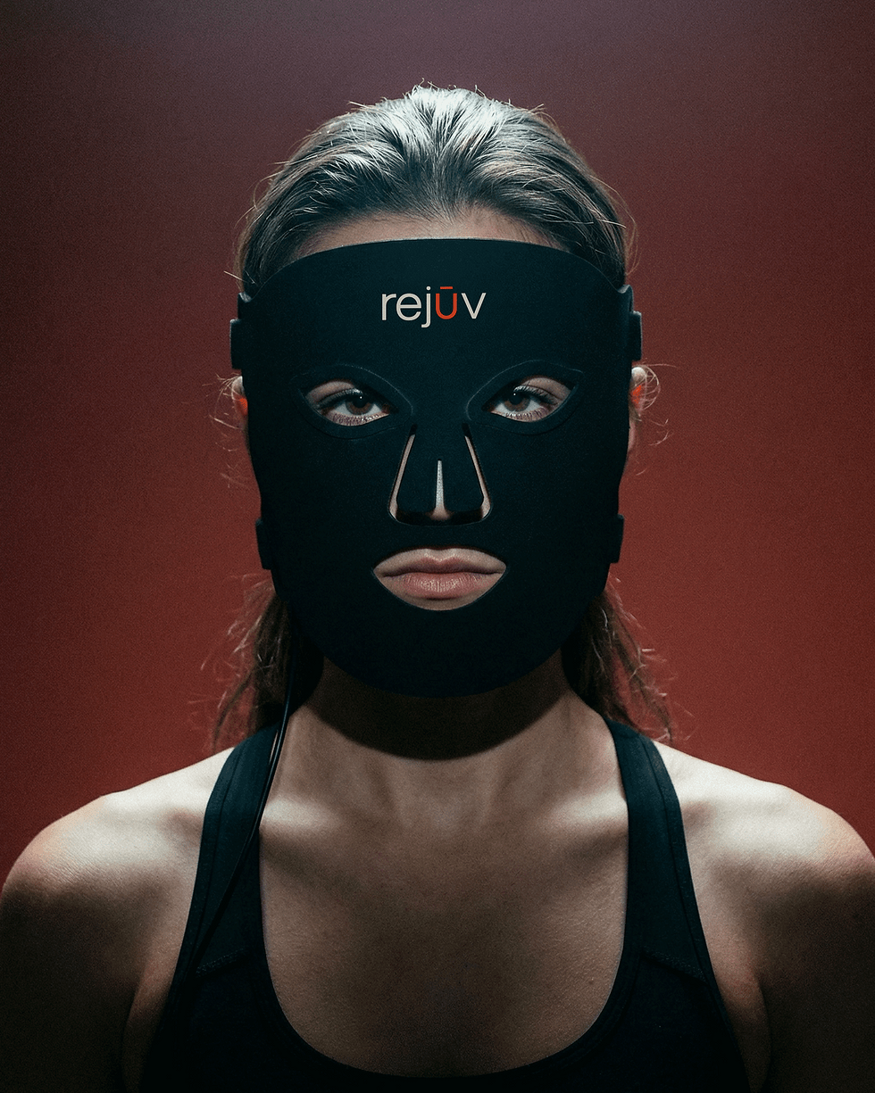 A model wearing Rejuv's red light LED face mask against a dark background.