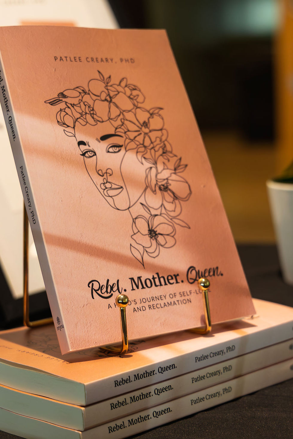 Rebel. Mother. Queen. book by Patlee Creary, PhD on display stand.