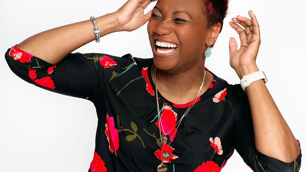 A woman with red hair laughs joyfully, wearing a floral top and striped pants. She accessorizes with bracelets and a necklace, set against a white background.
