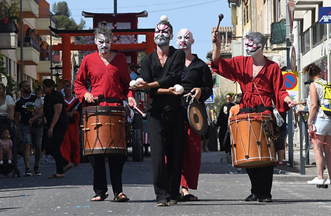 Spectacle de rue japonais avec jongleur entouré de musiciens percussionnistes en costume traditionnel