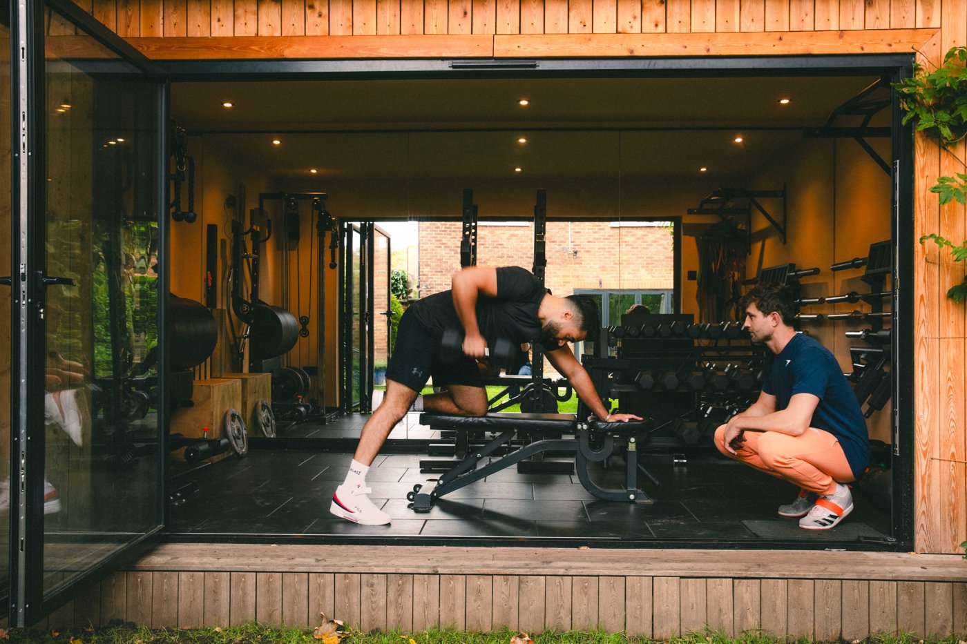 Jack coaching a client through a dumbbell row in the garden studio
