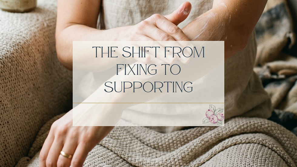 A woman in a natural linen tank top applies lotion to her forearm while seated on a textured neutral couch, a woven blanket across her lap. A gold ring is visible on her hand. The image is cropped to focus on her arms and torso. A semi-transparent cream overlay in the center displays the blog title "The Shift From Fixing to Supporting" in dark slate serif lettering, with a small Juneberry Apothecary botanical berry illustration in the lower right corner of the text box.