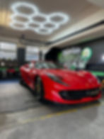 Ferrari rouge dans l’atelier MyCarCleanEco, avec les reflets des éclairages sur la carrosserie.