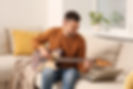 Man learning to play guitar with online music course at home. Time for hobby.jpg