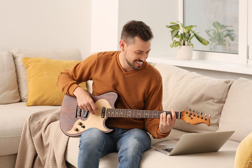 Man learning to play guitar with online music course at home. Time for hobby.jpg