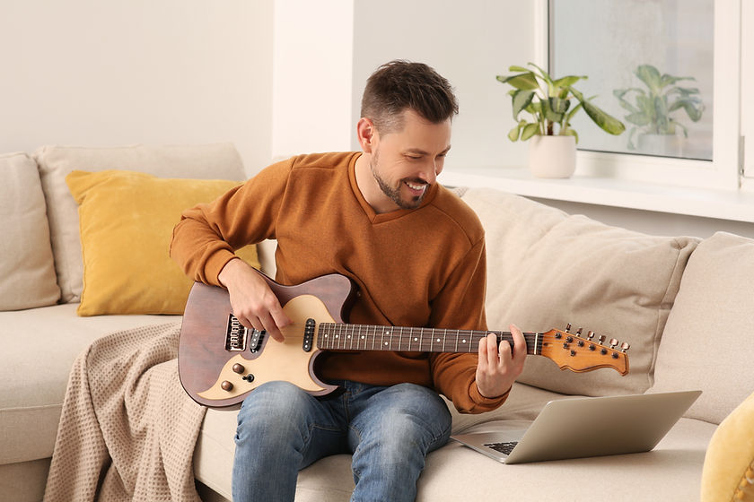 Man learning to play guitar with online music course at home. Time for hobby.jpg