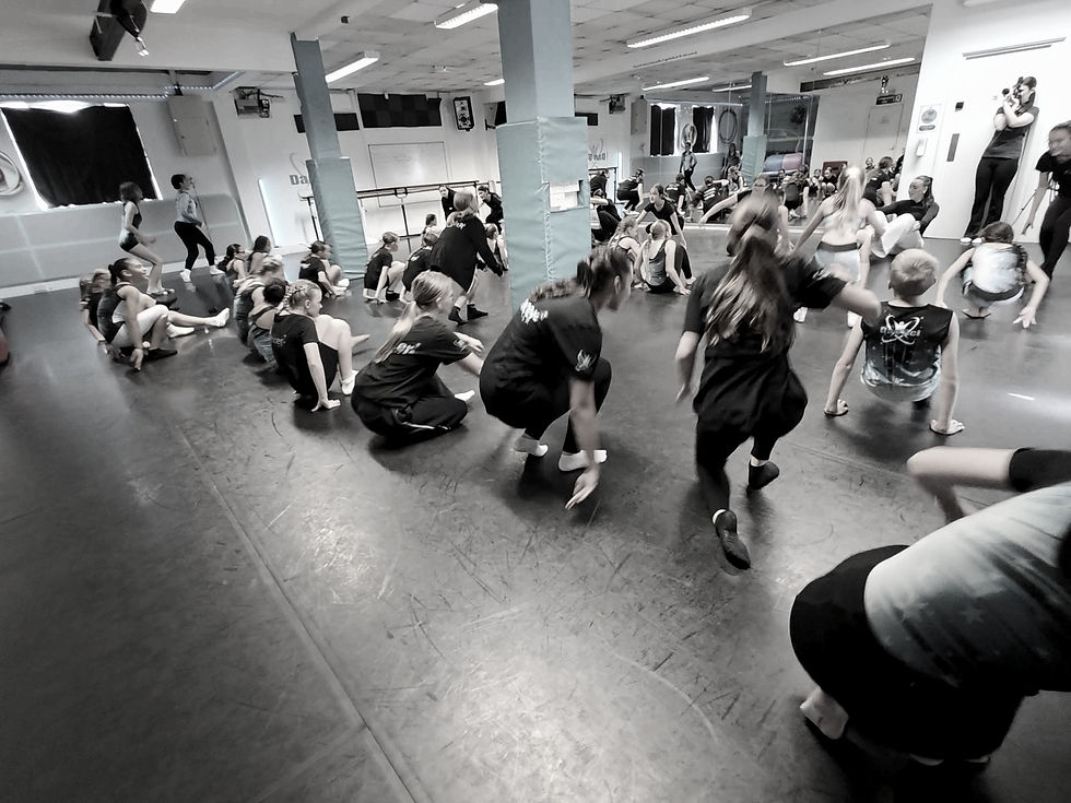Wide angle view of a dance studio filled with students engaging in a dance class