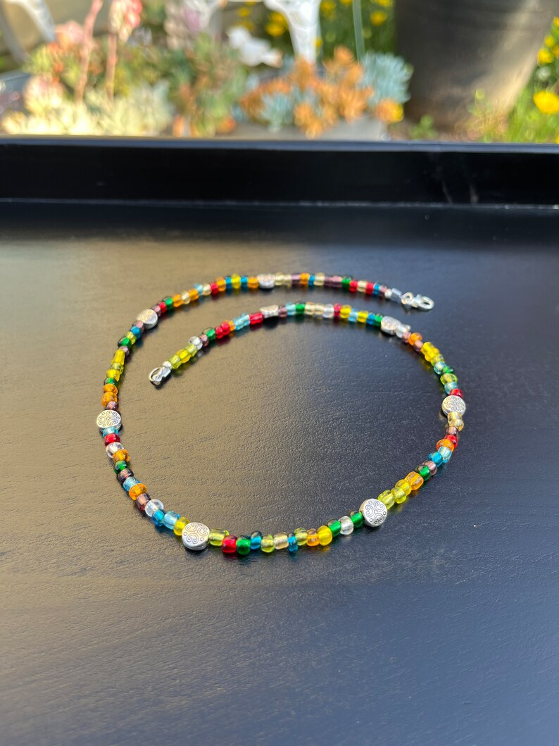 colorful necklace on a black surface before a window