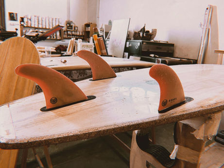 thruster fin setup on a handcrafted wooden surfboard