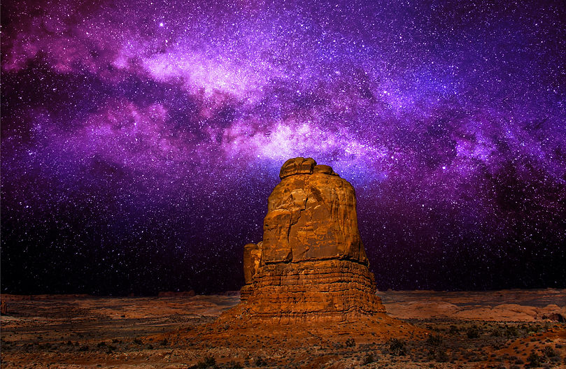 An astrophotography image of a mountain under the nght sky and the milky way galaxy.