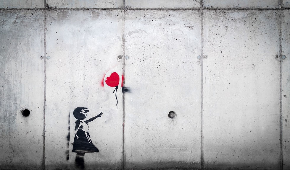 Painting on cement wall of a girl releasing a heart-shaped balloon