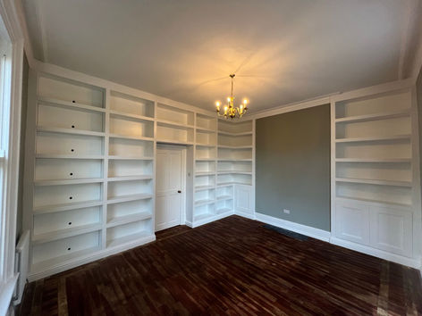 Bespoke white shelving units surrounding the walls with original parquet flooring