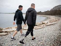 זוג גברים מטיילים בחוף, לאחד מהם יש רגל תותבת