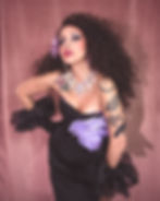 La Vedette in black strapless dress, curly hair, and tattoos