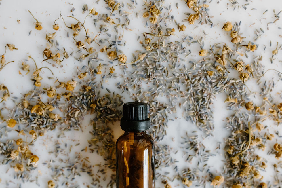 Dried chamomile flowers around a brown glass bottle.