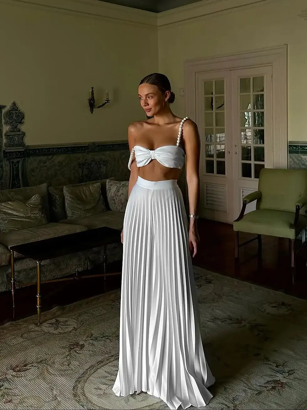 Woman in white strapless top and pleated pants in a living room