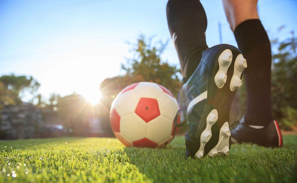 Close-up of a soccer player’s cleated shoe next to a red-and-white football