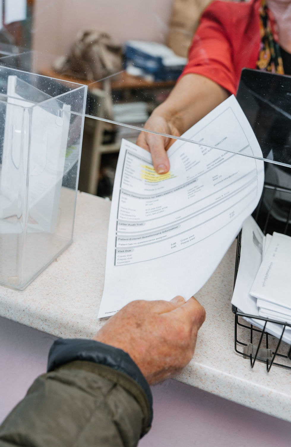 Patient receiving registration paperwork at the front desk before a first doctor visit at a medical clinic.