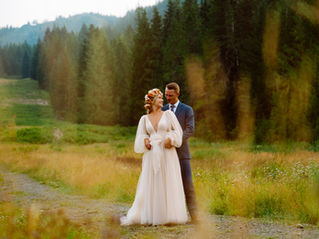 Bride and groom stand in the middle of a hiking path sharing an embrace among towering evergreen trees at Mt. Hood Skibowl.