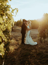 Bride and groom standing in the middle of a vineyard sharing a moment alone with the start of golden hour as a backdrop.