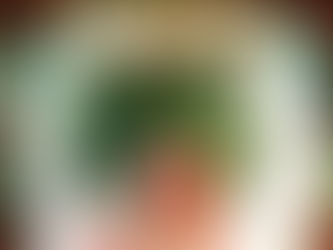 Bride and groom sitting under a mandap, or altar, at a cultural wedding. The altar consists of four pillars covered in drapery and colorful florals with greenery.