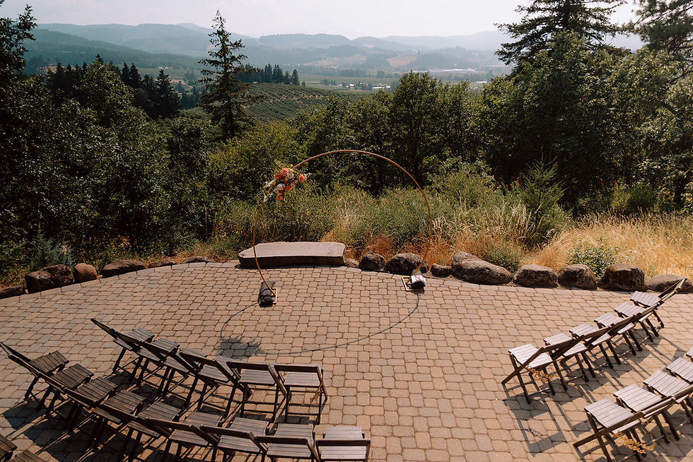 Ceremony set up including a rounded arch with a floral arrangement attached and views of the well known Hood River vineyards.