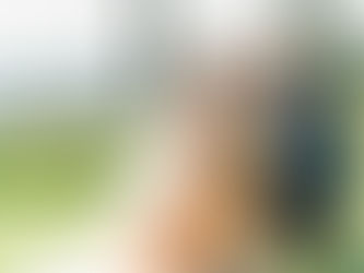 Bride and groom kneeling down to pet their dog, exchanging loving looks with greenery and hills as a backdrop.