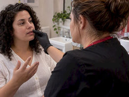 Esthetician assesses facial skin before waxing