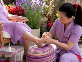 Nail technician performing reflexology pedicure on client