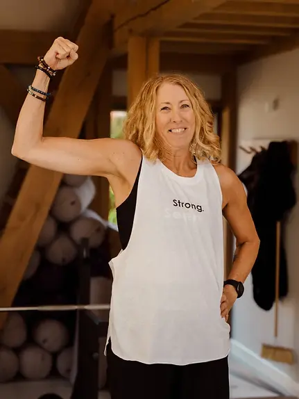 A woman flexes her arm proudly during a Holsm strength training session, highlighting confidence, capability, and the empowering approach Holsm brings to women building long-term strength and sustainable habits.
