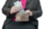 A woman putting a larger stack of hundred-dollar bills into her purse.