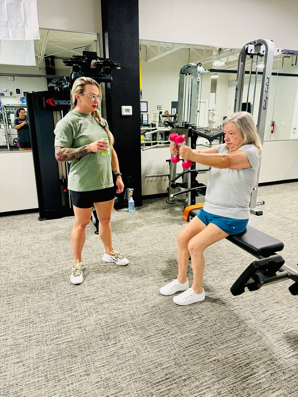 Trainer watching her elderly client sit on a bench and workout with dumbbells