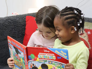 Two toddlers reading a book together on the classroom couch at Everstar Academy
